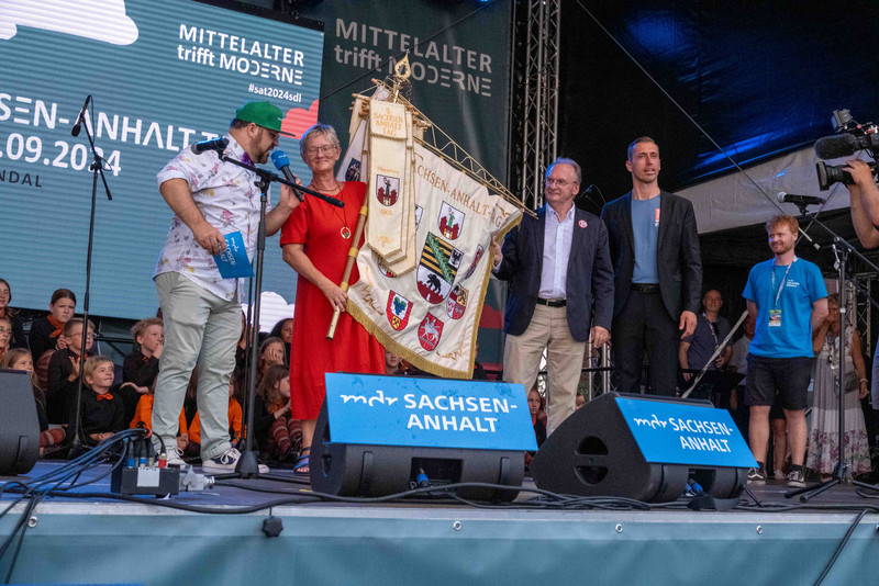 Ministerpräsident Dr. Reiner Haseloff übergibt die Sachsen-Anhalt-Fahne an die Oberbürgermeisterin der Stadt Bernburg.